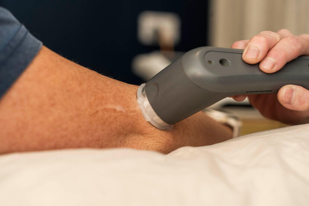 Person with a knee scar receiving scar release therapy using therapeutic ultrasound to improve tissue mobility