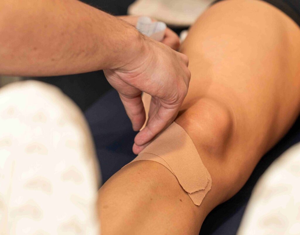 Physiotherapist applying therapeutic sports tape services to a patient’s knee at Wellers Hill Physio